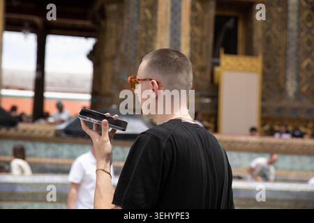 BANGKOK, THAILAND-MAY 16, 2026: Male tourist talking using smartphone, travel lifestyle and digital behavior, side profile Stock Photo