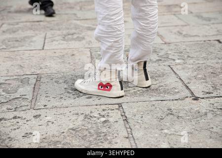 BANGKOK, THAILAND-MAY 16, 2026: Man in white high top sneakers standing on stone paving, Converse All Star sneakers, high angle view Stock Photo