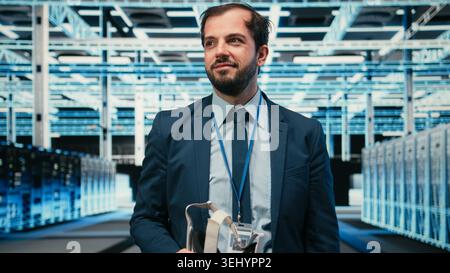 Cheerful data center technician removing VR goggles after finishing equipment rigs optimization. Jolly server farm expert pleased after using virtual reality technology to upgrade hardware, camera A Stock Photo