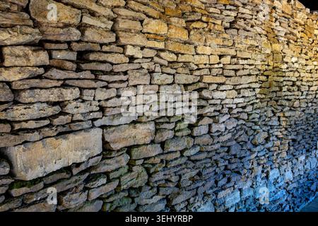 Detail of an ancient rustic dry stone wall texture showing layered rocks and weathered limestone surface Stock Photo