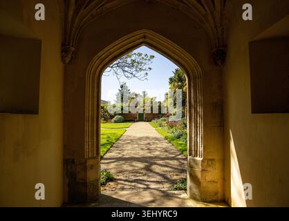 View through a stone arched doorway looking onto a manicured garden path on a sunny day Corsham court garden Stock Photo