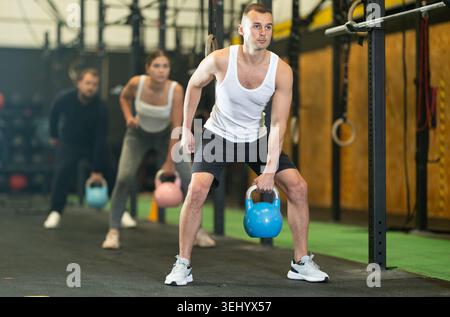 Sportive young man lifting heavy kettlebell in sports hall Stock Photo
