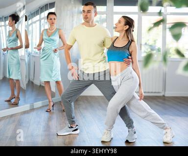 Woman and man in sportswear performing tango at dance rehearsal Stock Photo