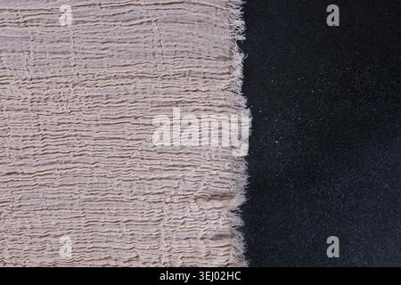 Beige Muslin Fabric with Frayed Edge on Black Background Stock Photo
