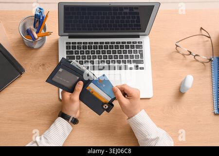 Male hands taking credit card from wallet at table, top view Stock Photo