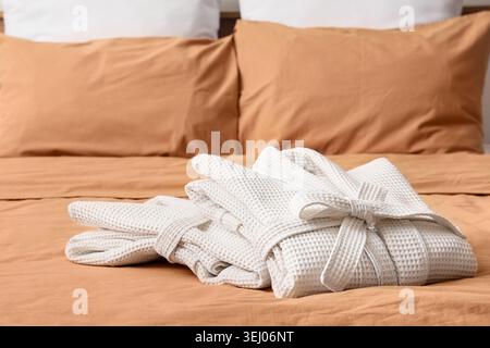Folded waffle bathrobes on bed in room Stock Photo