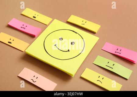 Sticky papers with drawings of different emotion faces on brown background Stock Photo
