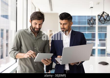 Team collaborating using digital devices in modern office Stock Photo