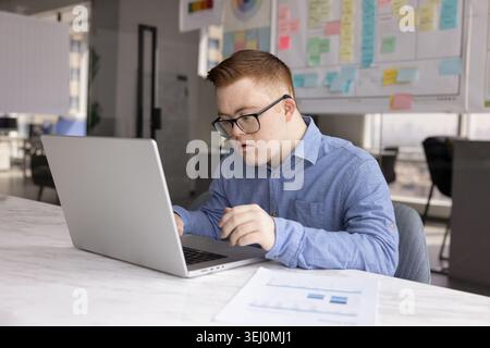 Young man with Down syndrome working in office Stock Photo