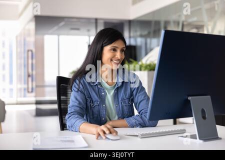 Young smiling woman focused in productive workflow using pc Stock Photo