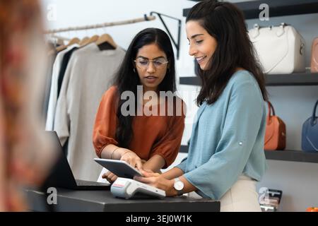 Female coworkers using tablet at checkout counter Stock Photo