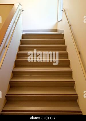 The stairwell shows safety handrails for an emergency exit in a nursing home building in Canada. The stairs lead to an exit door. Stock Photo