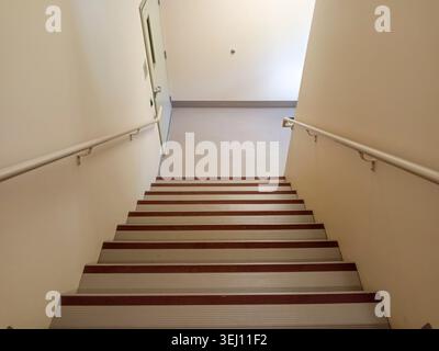 The stairwell shows safety handrails for an emergency exit in a nursing home building in Canada. The stairs lead to an exit door. Stock Photo