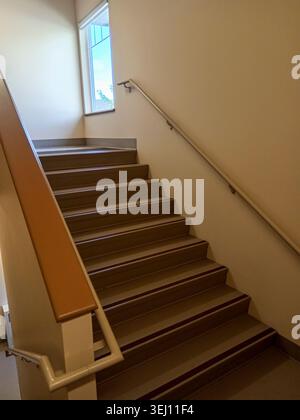 The stairwell shows safety handrails for an emergency exit in a nursing home building in Canada. The stairs lead to an exit door. Stock Photo