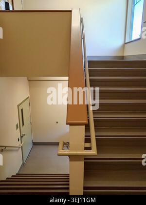 The stairwell shows safety handrails for an emergency exit in a nursing home building in Canada. The stairs lead to an exit door. Stock Photo