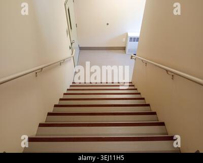 The stairwell shows safety handrails for an emergency exit in a nursing home building in Canada. The stairs lead to an exit door. Stock Photo