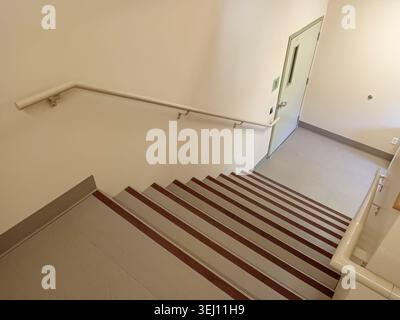 The stairwell shows safety handrails for an emergency exit in a nursing home building in Canada. The stairs lead to an exit door. Stock Photo