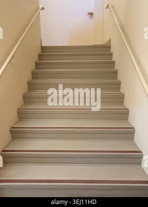 The stairwell shows safety handrails for an emergency exit in a nursing home building in Canada. The stairs lead to an exit door. Stock Photo