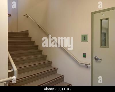 The stairwell shows safety handrails for an emergency exit in a nursing home building in Canada. The stairs lead to an exit door. Stock Photo