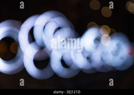 Abstract bokeh of glowing white rings on dark background Stock Photo