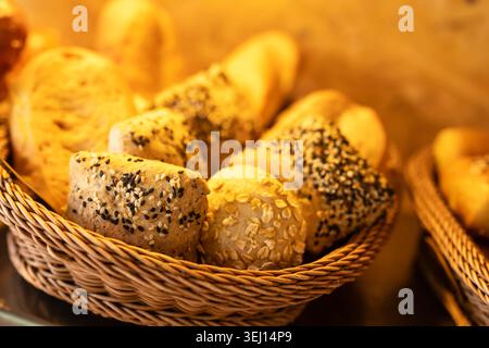 Assorted German wholegrain multigrain bread rolls with sesame and oat topping in wicker basket at affordable buffet restaurant Thailand Stock Photo