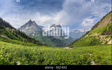 Epic Glacier National Park mountain valley with rugged snow‑capped peaks, lush green slopes and dramatic alpine scenery in Montana Stock Photo