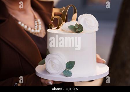 Elegant white cake decorated with roses for a fiftieth anniversary celebration or birthday party Stock Photo