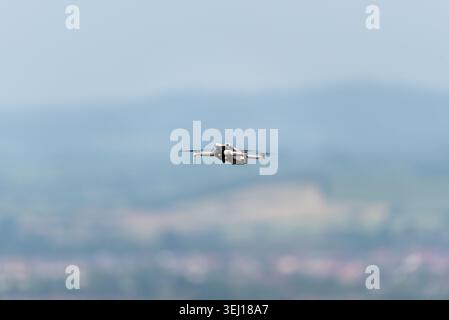 DJI Mini 4 Pro quadcopter drone flying above an event for filming work Stock Photo