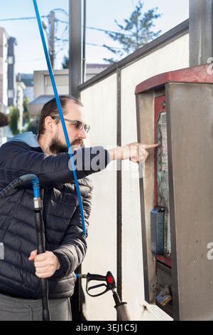 Man using self service car wash control panel outdoors Stock Photo
