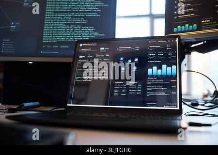 Close up of laptop displaying code, network analytics, cybersecurity dashboard in IT workspace. Supporting cloud security, DevOps, data monitoring, software marketing use Stock Photo
