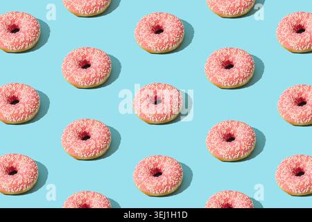 Pink donut pattern on light blue background. Creative food concept. Delicious dessert design idea. Stock Photo