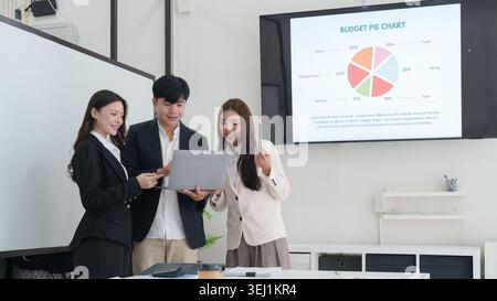 Asian business team reviewing budget pie chart on screen in office Stock Photo