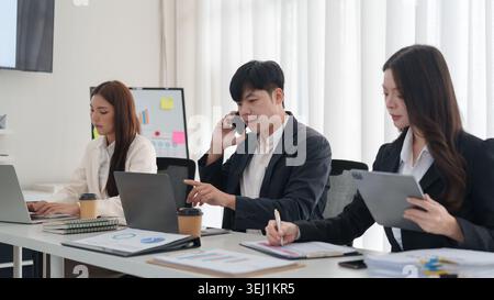 Asian business team collaborating on laptops in modern office Stock Photo