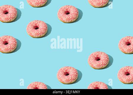 Pink donut pattern on light blue background with copy space. Creative food concept. Delicious dessert design idea. Stock Photo