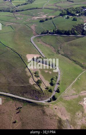 Aerial view of a winding S-shaped road cutting through lush green hills ...