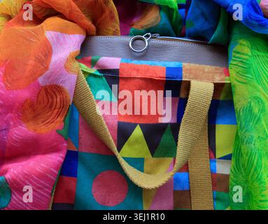 Vibrant colorful DIY tote bag with geometric patchwork pattern, flanked by bright silk scarves Stock Photo