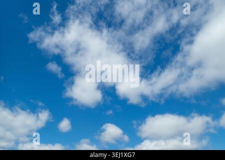 Fluffy white clouds drifting in a bright blue sky Stock Photo