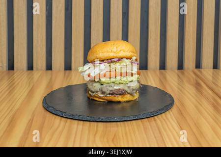A 200-gram organic beef patty, topped with a poached egg, crispy bacon strips, and a sprinkle of grated Parmesan cheese, all on a toasted seed bun. Stock Photo