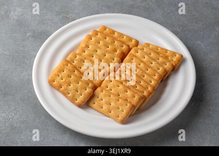 Crispy salted cream crackers arranged on a round white ceramic plate Stock Photo