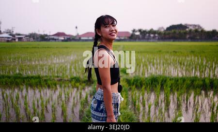 Young asian woman smiling while traveling in a rural rice field landscape Stock Photo