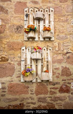 Rustic Wooden Fence Wall Decor with Tin Watering Cans and Flowers on a Stone Wall, Ayvalik - Cunda island Stock Photo