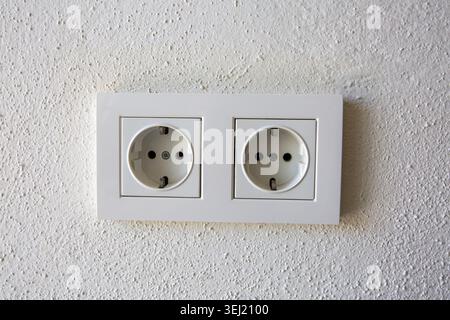 Double European Schuko Power Outlets on a White Textured Wall Stock Photo