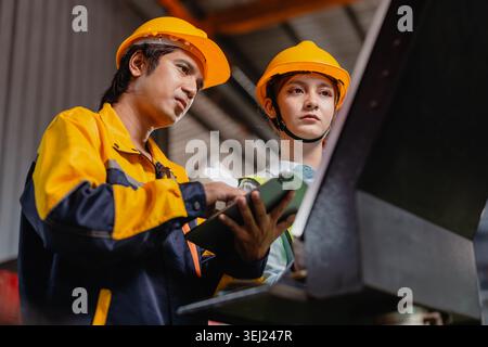 Engineers teamwork, Professional Engineer man and woman team working together in metal workshop plant factory in safety uniform and hardhat. Worker Ma Stock Photo