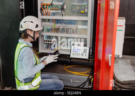 Industry Electrician, Modern technology industrial concept, Expert Engineer electricity technician female worker check inspecting electric wire in ele Stock Photo