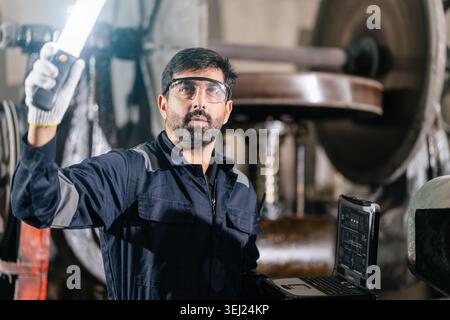 Mechanic Worker Hispanic Latin Indian male work service maintenance old Machine in metal plant heavy industry Stock Photo