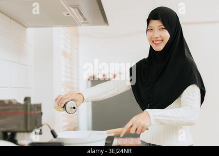 Arab Muslim Young woman cooking food at home kitchen happy smiling Stock Photo
