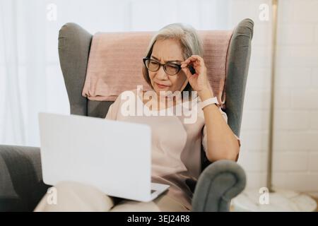 Senior woman using Laptop computer with stressed eyes pain posture Stock Photo