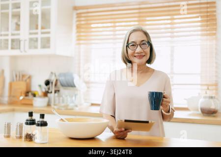 Senior Asian woman using Tablet computer modern technology, Portrait with cup of coffee happy smile Stock Photo