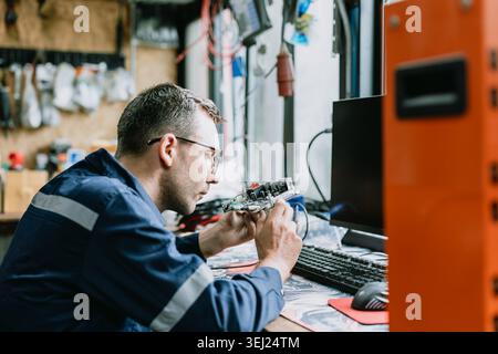 Professional electrician engineer male looking inspecting printed circuit board, Digital circuit hardware designer. Technology innovation working peop Stock Photo