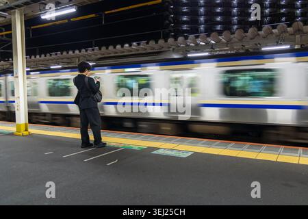 passenger waiting on train platform as subway rushes past Stock Photo
